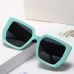 Square mint green oversized sunglasses with dark lenses on a white geometric stage