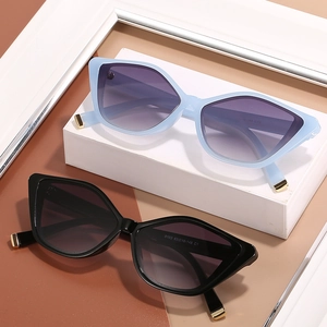 Stylish cat eye sunglasses with metal accents in light blue and black on minimalist stand