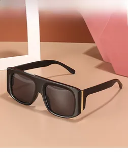 Detail of wide black oversized sunglasses with elegant gold metal accent on the temple