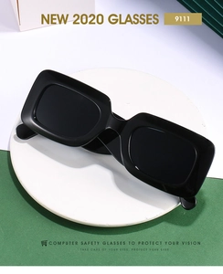 Gros plan sur lunettes de soleil rectangulaires noir mat avec larges branches sur support