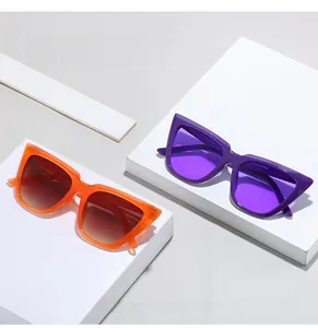 Detail view of cat-eye sunglasses with orange and purple frames on white blocks
