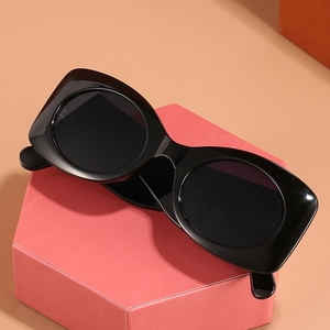 Chic black oval sunglasses with bold frames and round lenses on a pink display