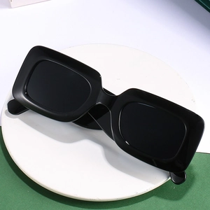 Lunettes de soleil carrées noires rétro avec branches larges sur support minimaliste