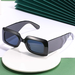 Lunettes de soleil rectangulaires noires chic avec branches larges ondulées sur socle