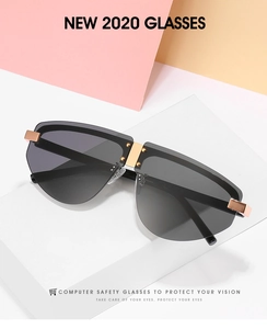 Close-up of frameless oversized sunglasses with dark grey lenses and gold metal details