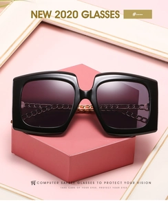 Detail of square oversized sunglasses featuring a unique gold chain bridge accent