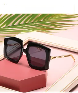 Detailed view of square sunglasses featuring distinctive gold chain temples on a black frame