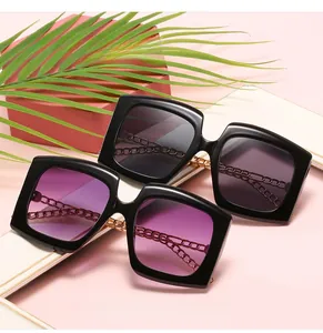 Detail of square oversized cat-eye sunglasses with luxury gold metal chain arms