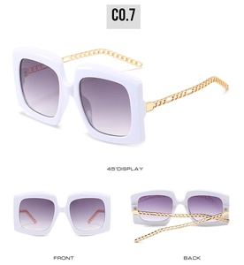 Detail view of white square sunglasses with gold metal chain temples and gradient lenses