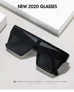 Detail of wide black oversized sunglasses with integrated dark lens and modern frames