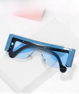 Detail of blue carbon fiber texture frame with gold rivets on oversized sunglasses