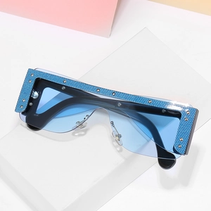Blue oversized one-piece sunglasses with rivet accents and carbon fiber texture frame