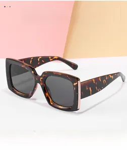 Detail of square tortoiseshell sunglasses with golden honeycomb metal trim on wide temples