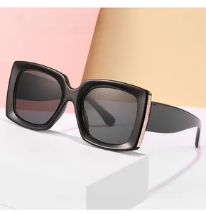 Detailed close-up of glossy black square sunglasses with textured gold metal temple hinges