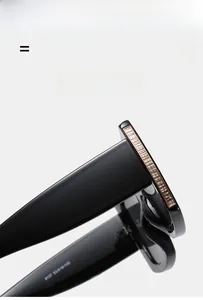 Detail view of black square sunglasses featuring gold textured metal hinge and wide temples