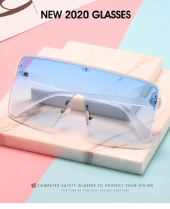 Detail view of large rimless shield sunglasses with blue gradient lenses on marble stand
