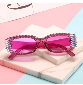 Detail view of pink rectangular sunglasses with hand-set rhinestones and spiked edges