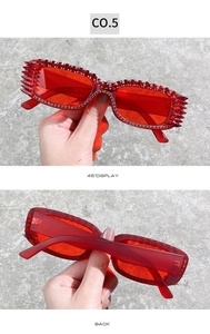 Detail view of red narrow sunglasses with hand-set rhinestones and spiked frame accents
