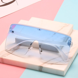 Oversized white frame sunglasses with light blue gradient lenses on marble stand