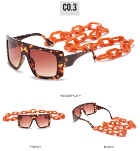 Macro view of tortoiseshell square sunglasses with bold orange acrylic chain accessory