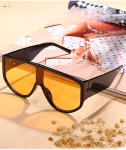 Close-up of oversized black frame sunglasses with vibrant orange lenses on vintage background