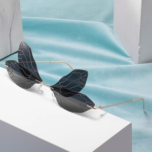 Steampunk dragonfly wing sunglasses with gradient lenses on minimalist display stand