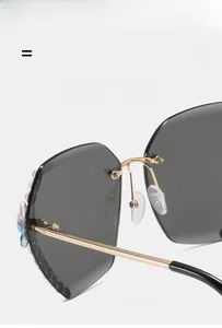 Détail de lunettes de soleil polygonales sans monture avec fleurs en cristal et métal doré