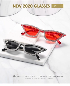 Detail of rhinestone cat eye sunglasses in black and red on marble display stand