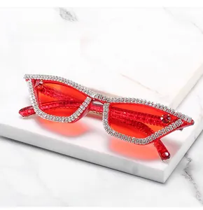 Macro detail of red cat-eye sunglasses with hand-set white diamonds on marble
