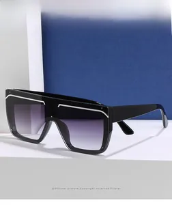 Close-up of oversized square sunglasses with metal trim on white geometric stand
