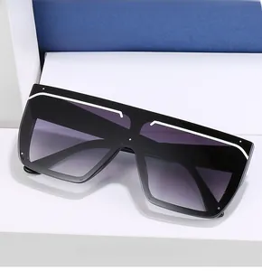 Detail of oversized square sunglasses featuring white top trim and gradient grey lenses
