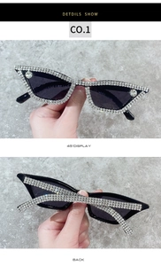 Detailed close-up of handmade cat eye sunglasses with rhinestones on a gray background