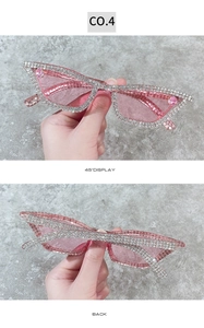 Detail of pink cat eye sunglasses featuring hand-set square rhinestones and pink gems