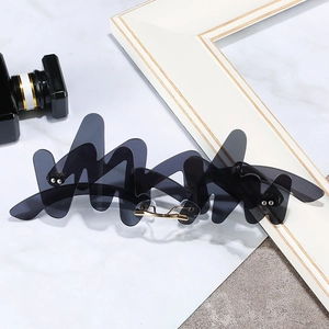 Futuristic wave shaped sunglasses with grey lenses and gold metal nose pads on marble