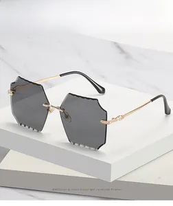 Detailed close-up of rimless square sunglasses with wave-cut edges and gold metal temples