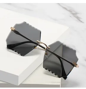 Detail view of rimless square sunglasses with grey hexagonal lenses and golden metal temples