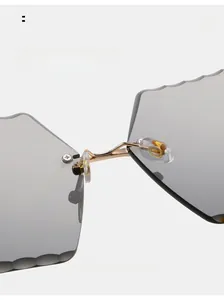 Close-up of rimless sunglasses with wavy scalloped gray lenses and golden metal bridge