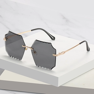 Frameless square sunglasses with scallop-edged grey lenses and golden metal temples