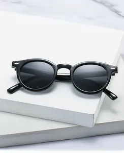Detailed close-up of retro black round frame sunglasses on a white decorative stone