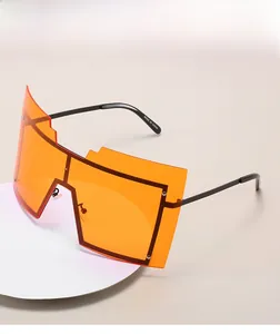 Détail de lunettes de soleil orange surdimensionnées avec verres géométriques et branches noires