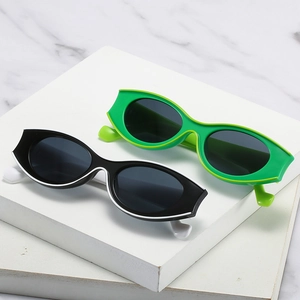 Trendy oval sunglasses with chunky black and green frames on marble background