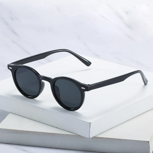 Classic black round frame retro sunglasses with silver rivets on a white marble background