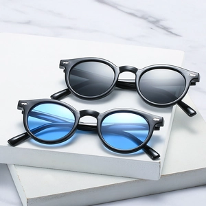 Retro round sunglasses with silver rivets featuring grey and blue lenses on marble