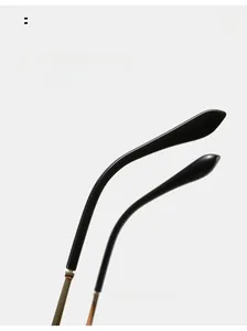 Detail of curved black glossy temple tips on rimless sunglasses with gold hinges