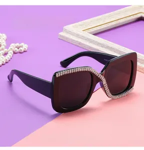 Detailed view of black square sunglasses with silver rhinestones on a decorative background