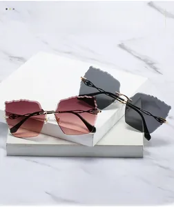 Detail of rimless sunglasses with wavy cut lenses and golden openwork metal temples