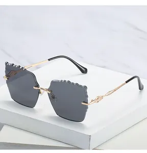 Detail of scalloped edge dark grey lenses and gold metal hollowed-out temples sunglasses
