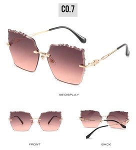 Detail view of rimless sunglasses with wavy edge gradient lenses and gold carved metal arms