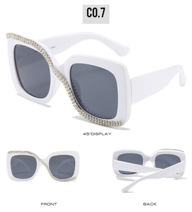 Macro detail of square white sunglasses featuring sparkling S-shaped rhinestone embellishments