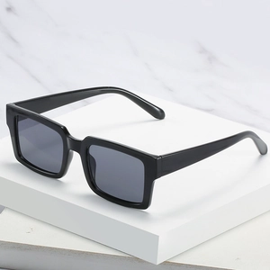 Lunettes de soleil carrées noires classiques avec verres gris foncé sur marbre blanc